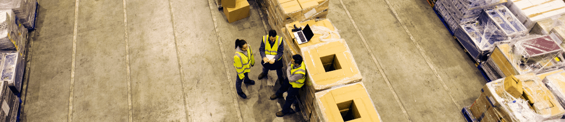Three workers talk to each other on a production floor