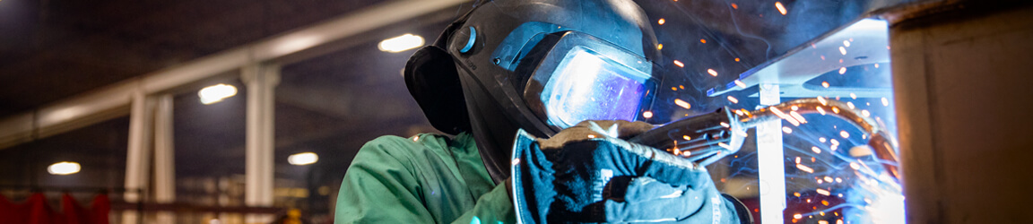 A welder uses a welding torch at an industrial worksite