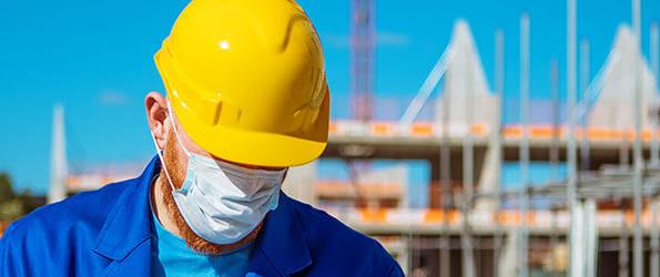 Ouvrier de la construction portant un casque protecteur et un masque