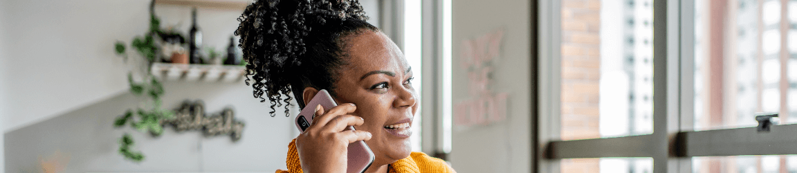 A woman in a yellow shirt talks on the phone