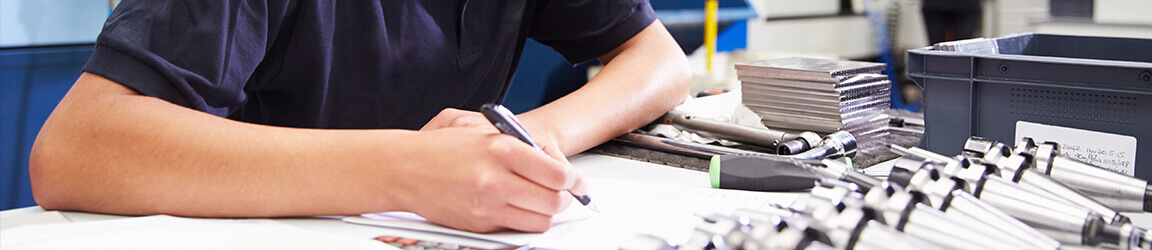Machinist drafting on a table that has tools strewn across it
