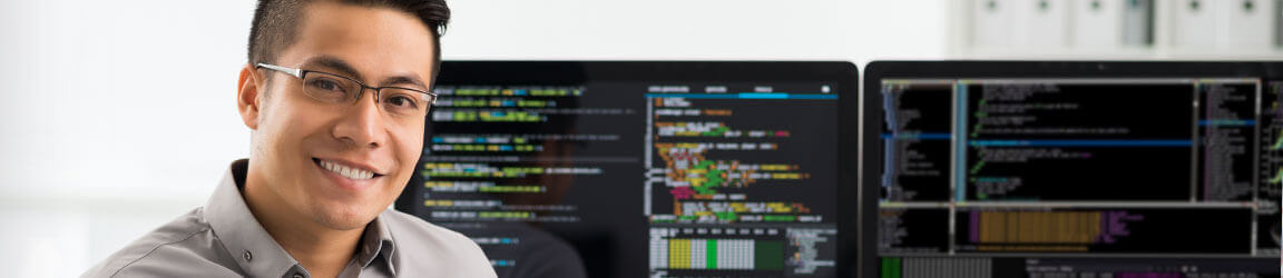 Man sitting in front of two computer monitors displaying code