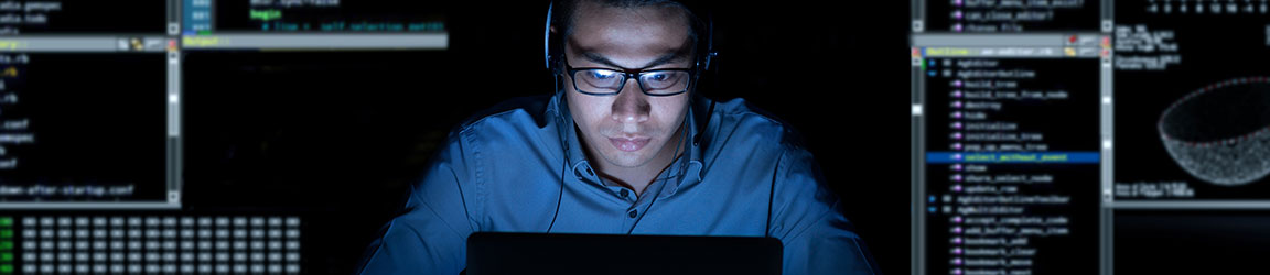 Man with headphones on computer coding