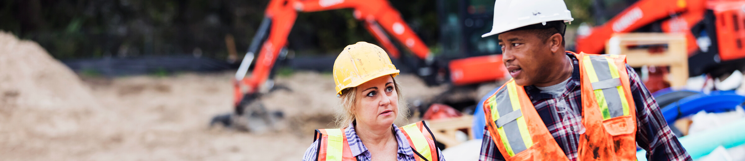 Two workers look at eachother on a construction site.