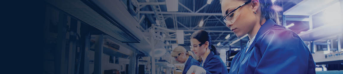 Women wearing blue uniforms and protective eyewear work on a line at a logistics company