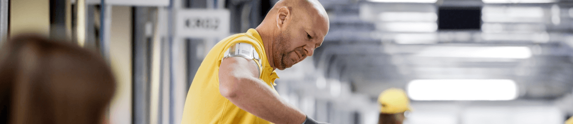 A man wearing a yellow uniform looks down in an industrial setting