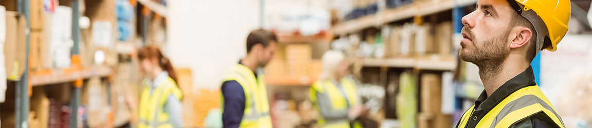 Warehouse workers working in a warehouse with hard hats and safety jackets