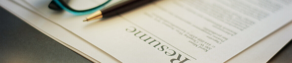 Pen and eyeglasses atop a resume