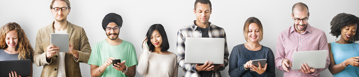 People standing against a wall using various electronic devices