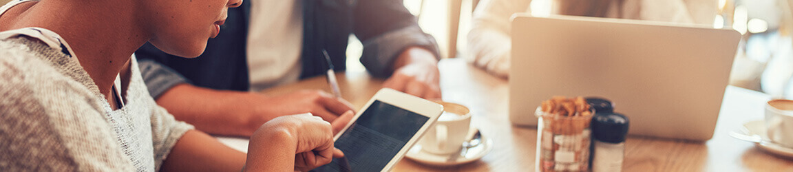 Small group of people using electronic devices in a coffee shop.